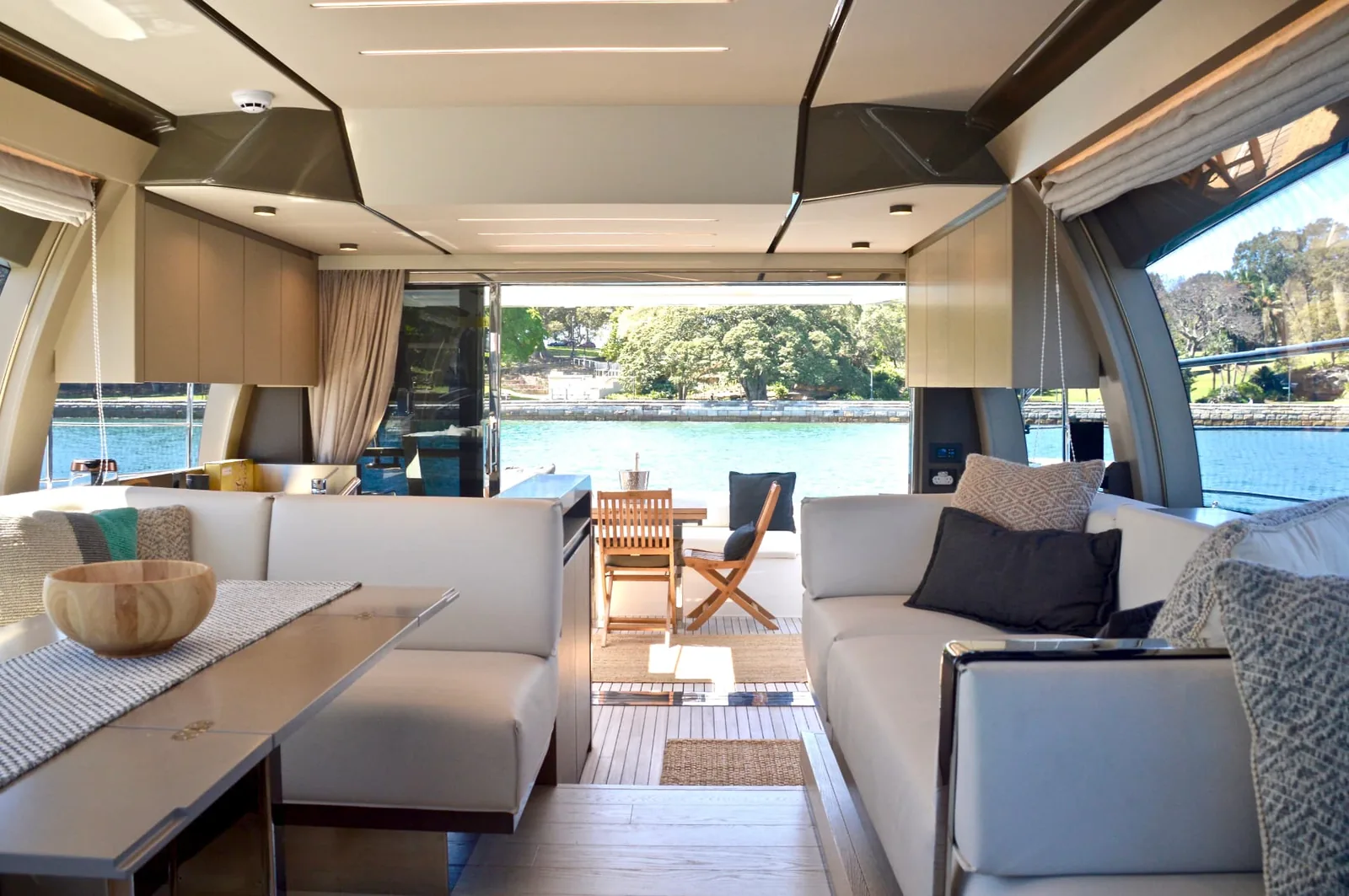 The Ribbon interior saloon with lounge seating and dining, opening onto the aft deck