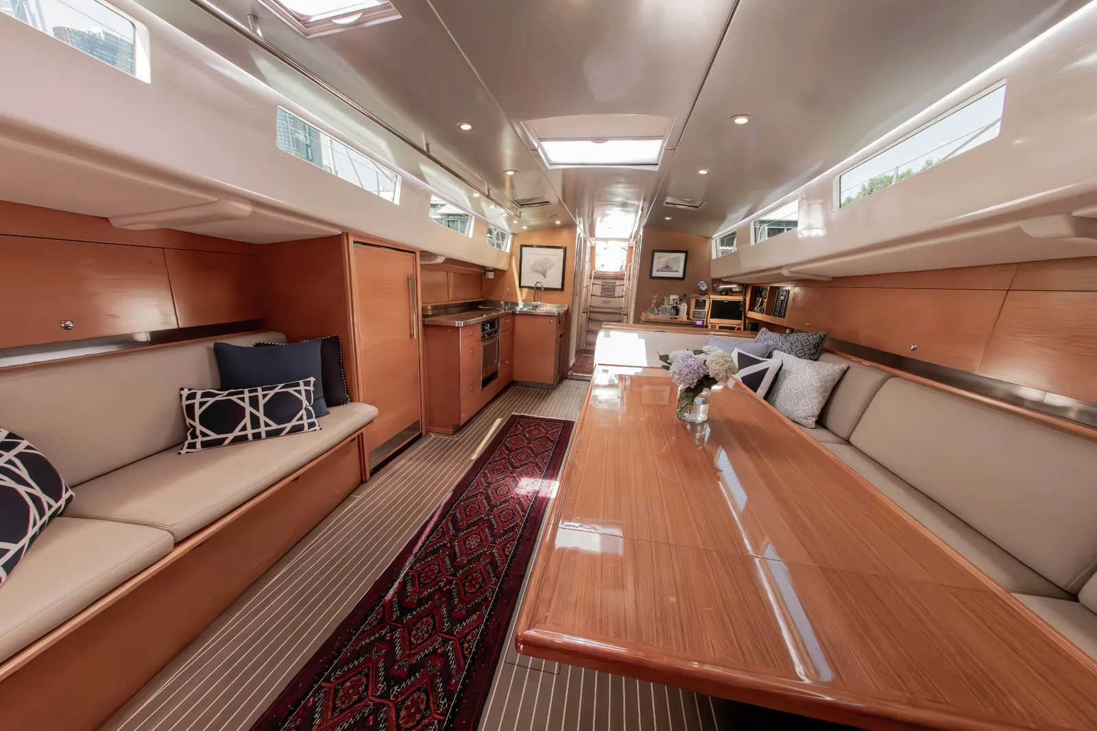 Sir Thomas Sopwith main saloon with a polished timber dining table, leather settees and galley beyond