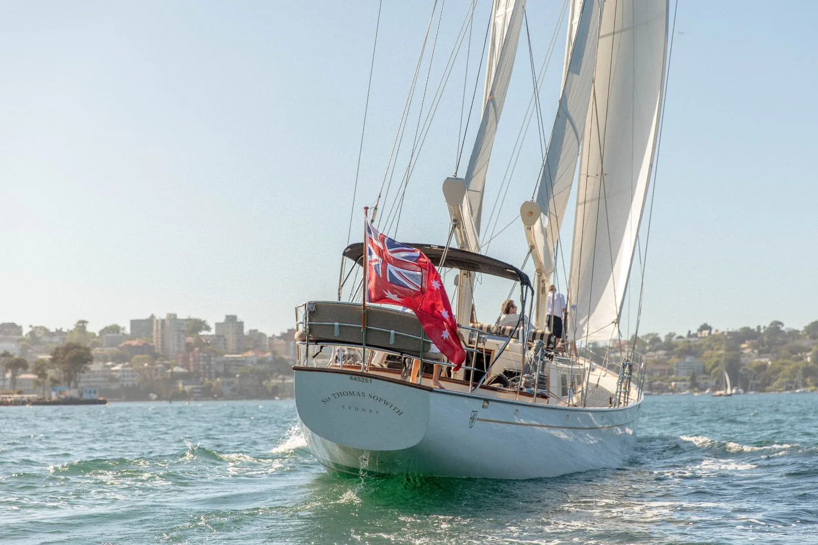 Sir Thomas Sopwith under sail on Sydney Harbour with guests in the cockpit
