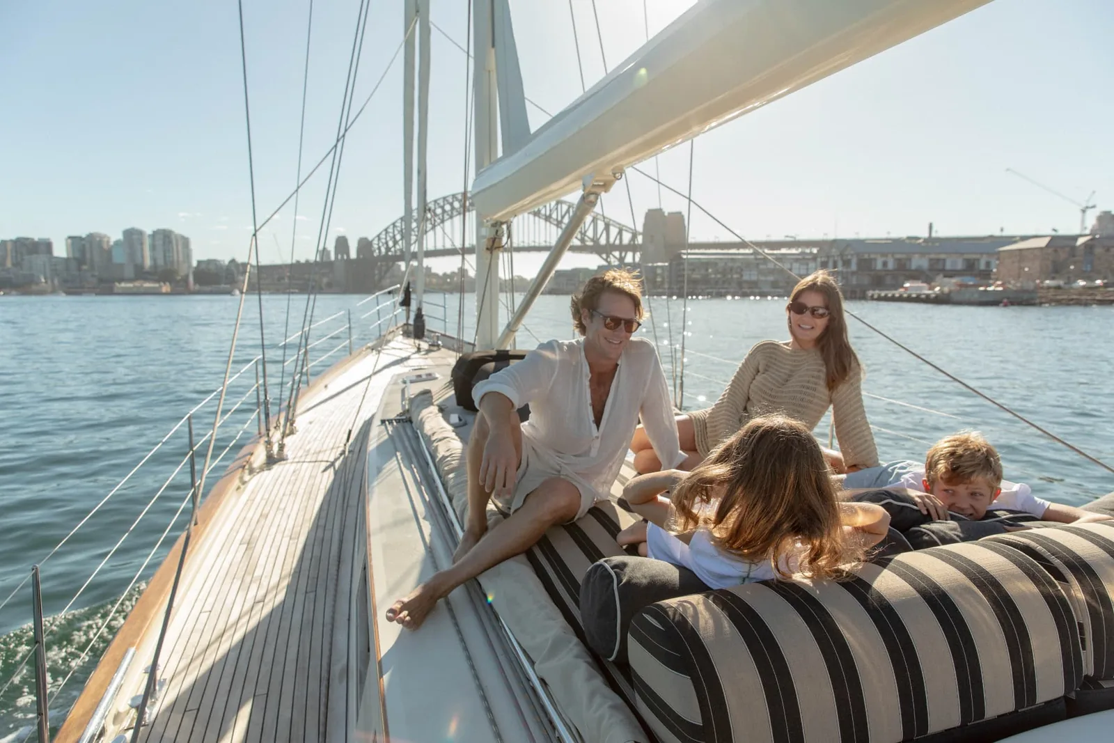 Guests relaxing on the side deck cushions of Sir Thomas Sopwith with the Sydney Harbour Bridge behind