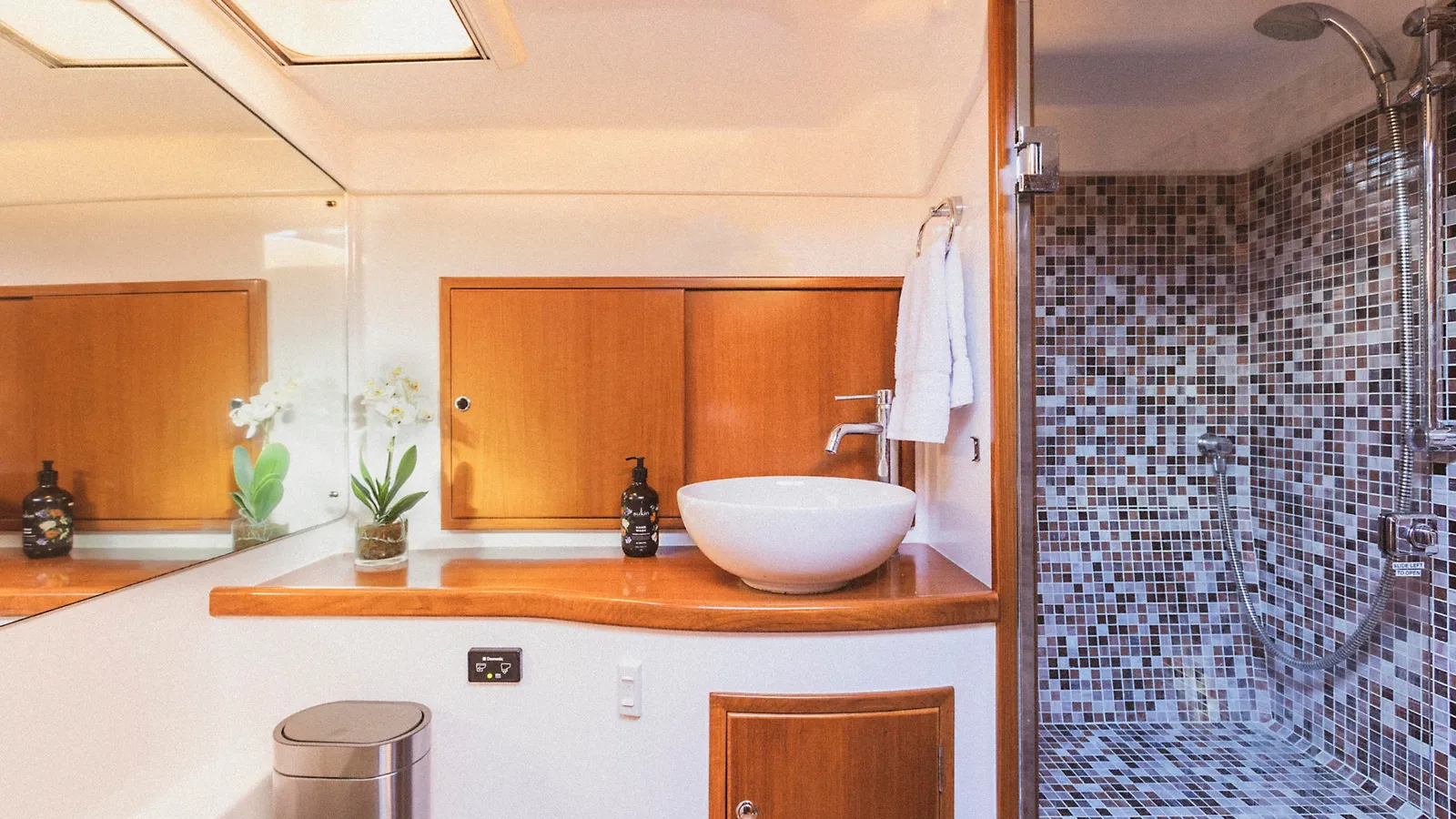 Felix's bathroom with timber vanity, basin and mosaic-tiled shower